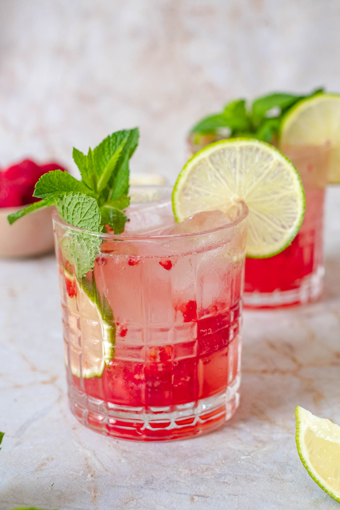 raspberry mojito mocktail served in a festive glass with extra mint and a lime wedge