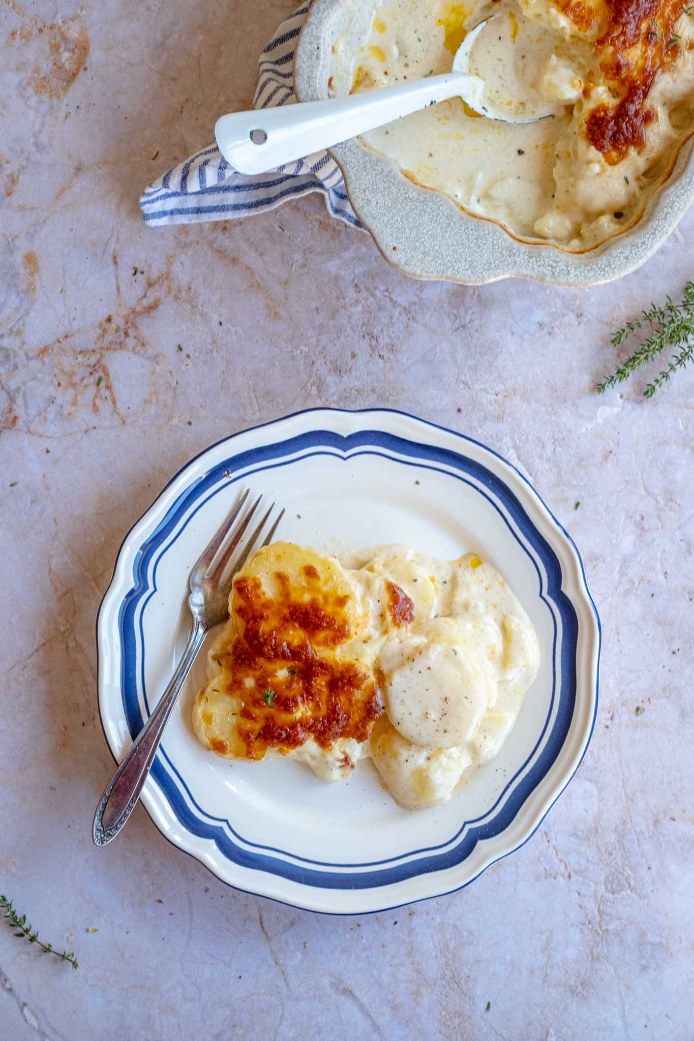 aardappel gratin op een bordje uitgeschept met in de hoek een ovenschotel